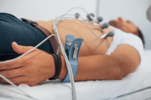 Man lying on the bed in the clinic and getting electrocardiogram test.