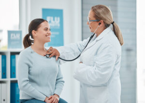 Women's health physician listening to heart beat of female patient