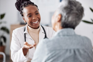 Smile, doctor consulting a patient in meeting in hospital for healthcare feedback or support. Happy, medical or nurse with a mature person talking or speaking of test results or advice