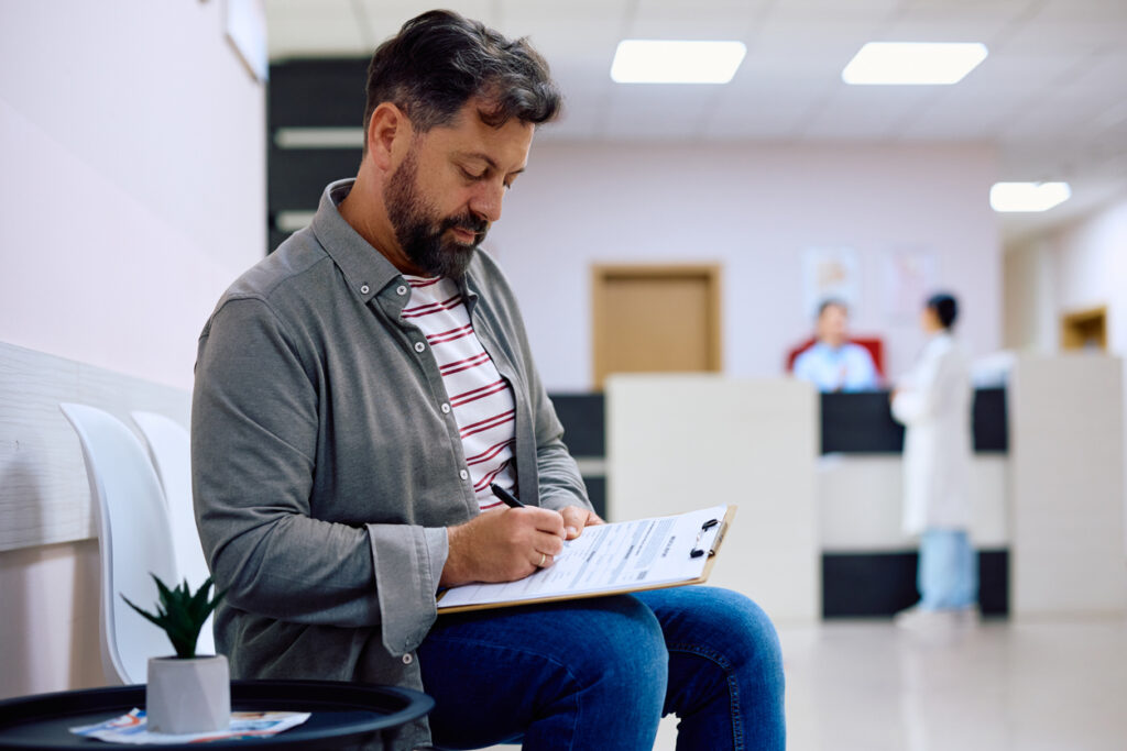 Male patients filling paperwork while checking in at urgent care.